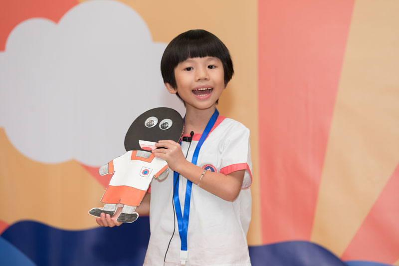 幼兒組決賽参賽者陳駿旻小朋友捧起有著黑色皮膚的紙偶 ，講「小黑」的故事。